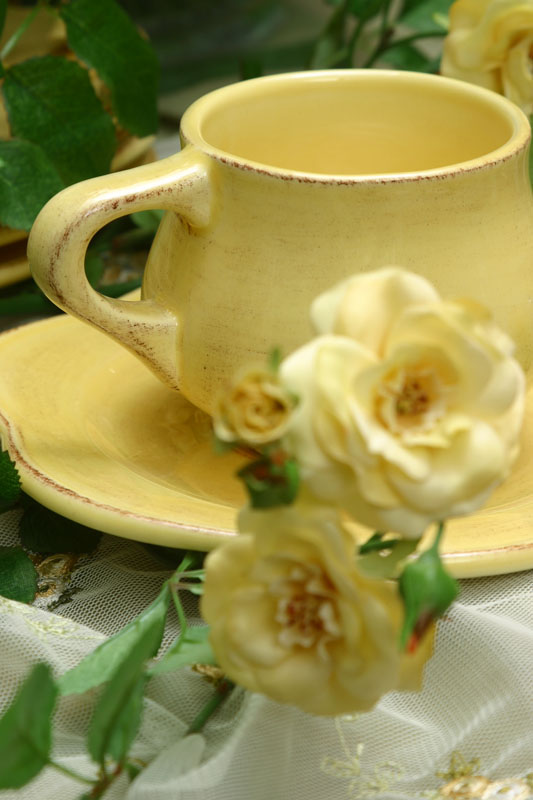 Yellow ceramic teacup and saucer set with yellow roses and white lace
