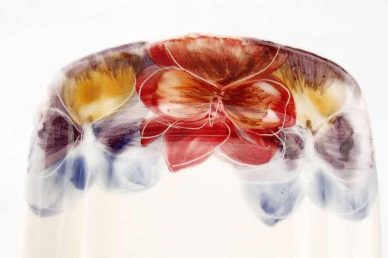 Close-up of a ceramic piece featuring a hand-painted floral design in red, yellow, purple, and blue