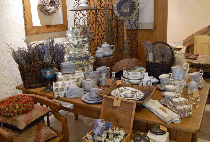 A shop display of rustic home decor featuring dried lavender, patterned ceramic tea sets, and wreaths